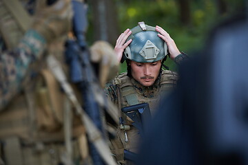 Image showing soldier preparing tactical and commpunication gear for action ba