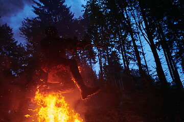 Image showing Soldier in Action at Night jumping over fire