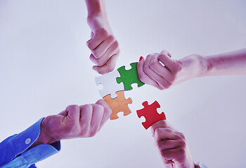 Image showing Group of business people assembling jigsaw puzzle