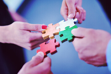 Image showing Group of business people assembling jigsaw puzzle