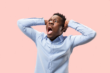 Image showing The young emotional angry man screaming on pink studio background