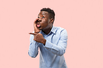 Image showing The young man whispering a secret behind her hand over pink background