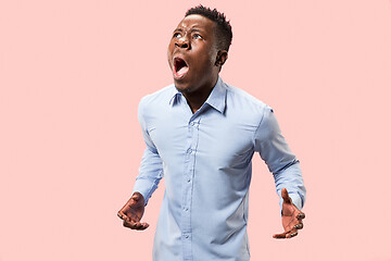 Image showing The young emotional angry man screaming on pink studio background