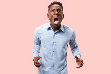 Image showing The young emotional angry man screaming on pink studio background