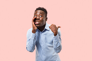 Image showing The young man whispering a secret behind her hand over pink background