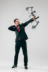 Image showing Businessman aiming at target with bow and arrow, isolated on white background