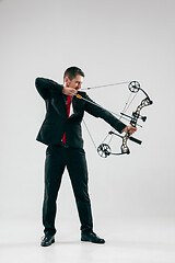 Image showing Businessman aiming at target with bow and arrow, isolated on white background