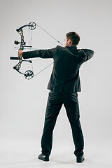 Image showing Businessman aiming at target with bow and arrow, isolated on white background