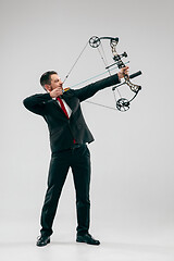 Image showing Businessman aiming at target with bow and arrow, isolated on white background