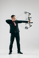 Image showing Businessman aiming at target with bow and arrow, isolated on white background