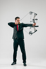 Image showing Businessman aiming at target with bow and arrow, isolated on white background