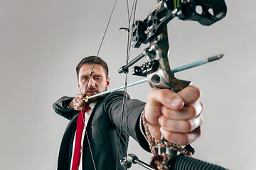 Image showing Businessman aiming at target with bow and arrow, isolated on white background