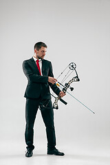 Image showing Businessman aiming at target with bow and arrow, isolated on white background