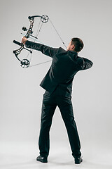 Image showing Businessman aiming at target with bow and arrow, isolated on white background