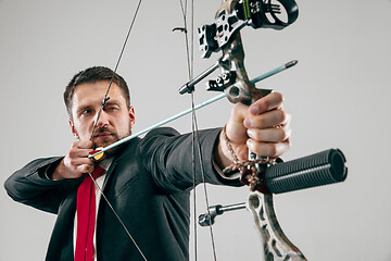 Image showing Businessman aiming at target with bow and arrow, isolated on white background