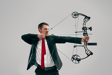 Image showing Businessman aiming at target with bow and arrow, isolated on white background