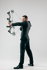 Image showing Businessman aiming at target with bow and arrow, isolated on white background