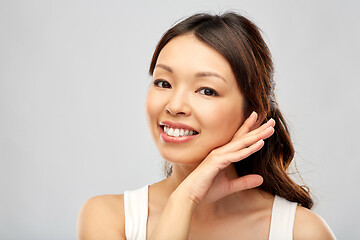 Image showing happy smiling young asian woman touching her face