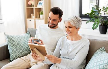 Image showing adult son and senior mother with photo at home