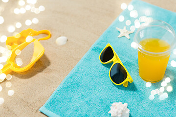 Image showing sunglasses, sand toys and juice on beach towel