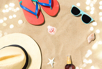 Image showing straw hat, flip flops and sunglasses on beach sand