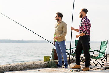 Image showing male friends with fishing rods and beer on pier