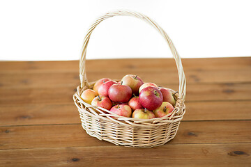 Image showing ripe apples in wicker basket on wooden table