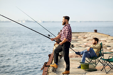 Image showing happy friends with fishing rods on pier