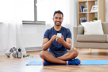 Image showing indian man with smartphone on exercise mat at home