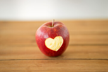 Image showing red apple with carved heart shape on wooden table