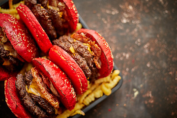 Image showing Set of four homemade giant double becon cheese burgers. Served with french fries on wooden board.