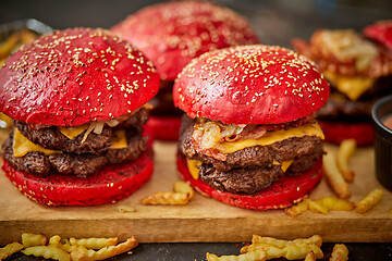 Image showing Set of four homemade giant double becon cheese burgers. Served with french fries on wooden board.