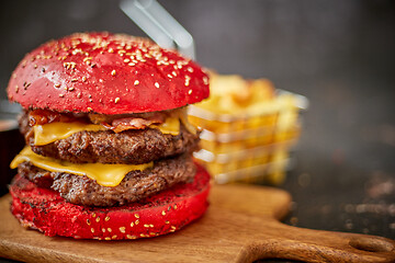 Image showing Homemade red sesame bun double bacon cheese burger. Served with french fries on wooden board.