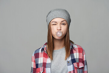 Image showing Smiling teen girl blowing bubblegum winking at you