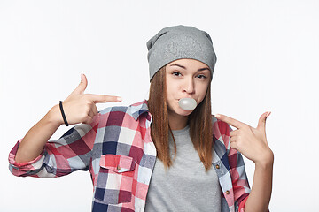 Image showing Closeup of cheeky teen girl blowing bubblegum and pointing at it