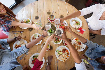 Image showing friends eating and clinking glasses at restaurant