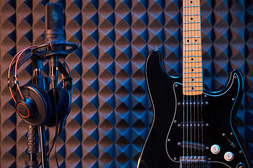 Image showing Black electric guitar and microphone with professional headphones