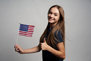 Image showing Happy female holding USA flag and gesturing thumb up