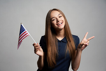 Image showing Happy female holding USA flag and gesturing Victory