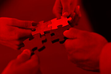 Image showing Group of business people assembling jigsaw puzzle