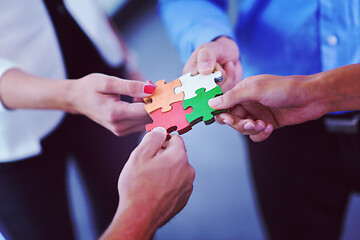 Image showing Group of business people assembling jigsaw puzzle