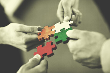 Image showing Group of business people assembling jigsaw puzzle