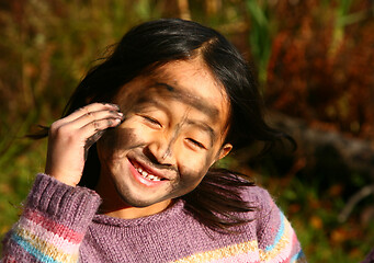 Image showing Portrait of a young cute girl looking at the camera putting coal