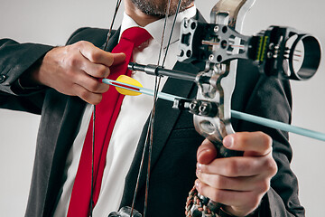 Image showing Businessman aiming at target with bow and arrow, isolated on white background