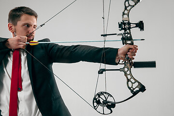 Image showing Businessman aiming at target with bow and arrow, isolated on white background