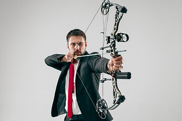 Image showing Businessman aiming at target with bow and arrow, isolated on white background