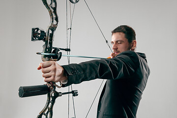 Image showing Businessman aiming at target with bow and arrow, isolated on white background