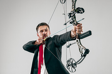 Image showing Businessman aiming at target with bow and arrow, isolated on white background