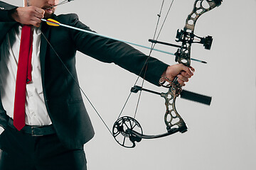 Image showing Businessman aiming at target with bow and arrow, isolated on white background