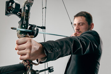 Image showing Businessman aiming at target with bow and arrow, isolated on white background